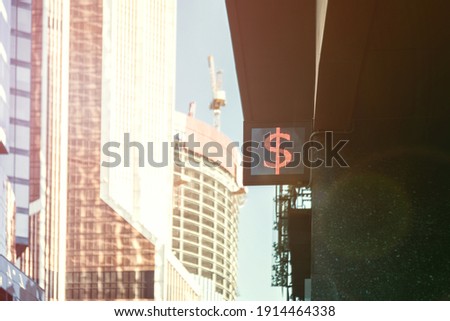 Currency euro or dollar sign on singboard against blue sky and buildings on background. Business stocks news concept.