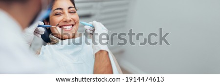 Happy woman getting dental checkup at dentistry. Dentist using dental equipment for examination of teeth of a female patient. Royalty-Free Stock Photo #1914474613