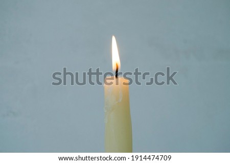 burning candle on gray background