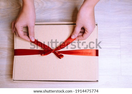 Female hands close-up, holding a gift in a box with a red ribbon. Concept - Valentine's Day, Women's Zhenya, Birthday, Mother's Day.