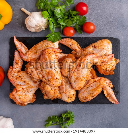 Raw marinated chicken wings with spices and vegetables. Top view, closup Royalty-Free Stock Photo #1914483397