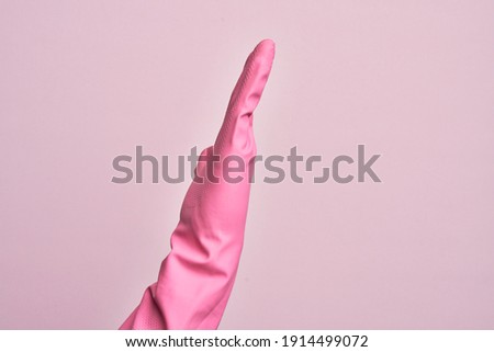 Hand of caucasian young man with cleaning glove over isolated pink background showing side of stretched hand, pushing and doing stop gesture