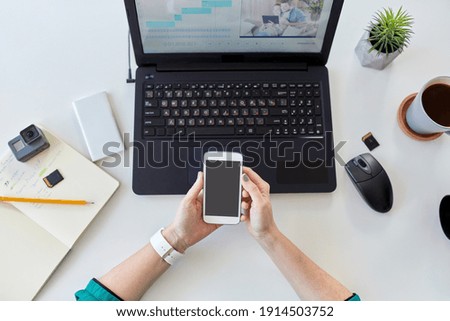 technology, post production and vlog concept - close up of woman with smartphone and laptop computer working at home office