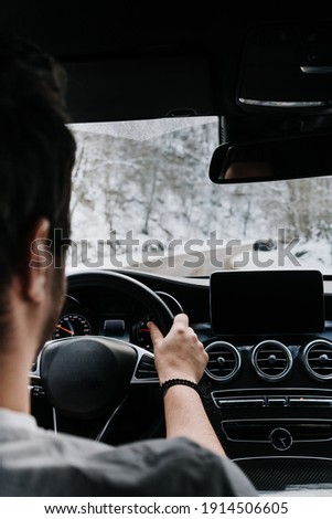 Caucasian male driver details - driving car on the empty road, winter and snow background


