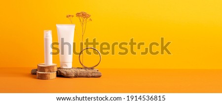 Group of cosmetic tubes bottles podium from natural materials orange background
