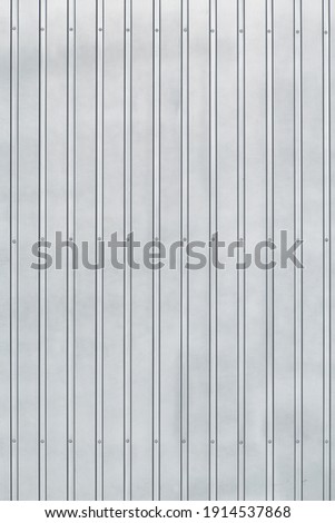 A metal surface with corrugations and rivets, illuminated with natural light. for industrial background. vertical position.