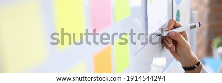 Woman draws charts on white board and holds presentation. Small and medium business development and training concept Royalty-Free Stock Photo #1914544294