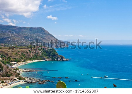 Amazing tropical panoramic view of turquoise gulf bay, sandy beach, green mountains and plants, blue sky white clouds background, cliffs platform Cape Capo Vaticano, Calabria, Southern Italy.