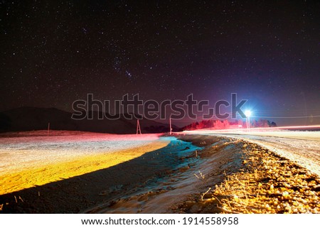 A colourful long exposure nightshot landscape with mountains and road in winter