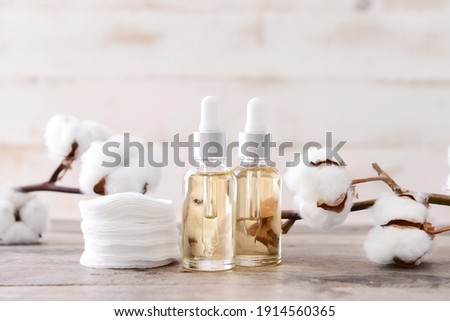 Bottles of cottonseed oil with cosmetic pads on table