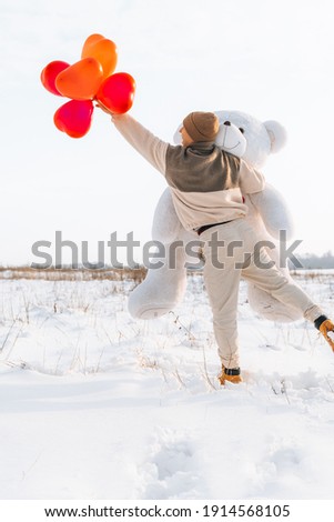 Candid millennial man holding big teddy bear soft toy gift heart air balloons on this special day surprising wife. romantic present for Birthday, Christmas, Valentine's Day and Women's Day.