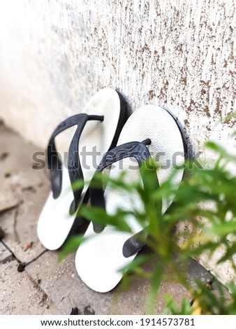 flip-flops from Indonesia, which is known as the "swallow"sandal. Very comfortable to use and cheap price. Served on white wall with foreground Royalty-Free Stock Photo #1914573781