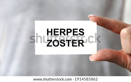 the doctor's gloved hands hold a card with text HERPES ZOSTER, Medical concept