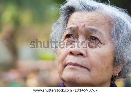 Senior woman with short gray hair and looking up while standing in a garden. Space for text. Concept of aged people and healthcare. Royalty-Free Stock Photo #1914593767