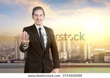 Asian businessman with hand gesture on the rooftop with skyscrapers background