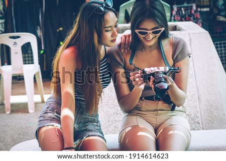 Chinese Tourist showing photography from camera with her friend in theme park