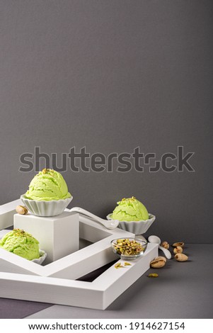 Scoop of homemade pistachio ice cream in white bowl with chopped pistachios. Healthy summer food concept with copy space