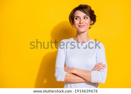 Photo of shiny sweet young lady dressed white shirt arms crossed looking empty space isolated yellow color background