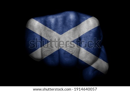 Flag of Scotland painted on strong fist on black background