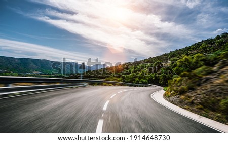Empty long mountain road to the horizon on a sunny summer day at bright sunset - speed motion blur effect Royalty-Free Stock Photo #1914648730