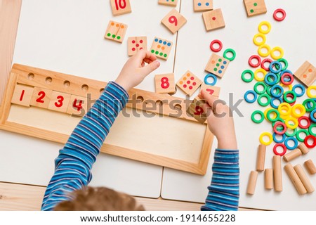 Child playing with different color wooden rings. Sequence, fine motor skills, therapy task for education and brain exercise. Counting math play game.  Montessori type implement. Wooden toys. Royalty-Free Stock Photo #1914655228