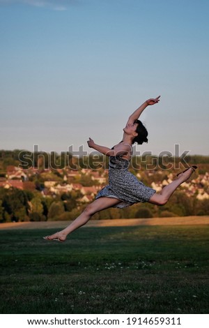A beautiful young female dancer jumping high towards  the blue sky