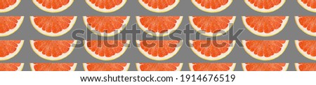 Seamless pattern of grapefruit slices as patterns on a grey background. collage. pattern with citrus print. Exotic wallpaper. Background of red grapefruit