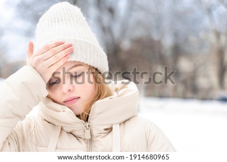teen girl has a headache outdoors in winter, copy spase Royalty-Free Stock Photo #1914680965