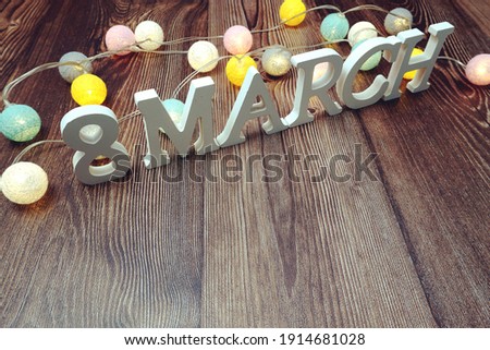 8 March Womens Day alphabet letters and LED cotton balls decoration on wooden background