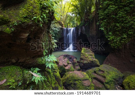 Beautiful waterfall in rainforest. Tropical landscape. Slow shutter speed, motion photography. Foreground with big stones. Nature concept. Travel and adventure. Suwat waterfall, Bali, Indonesia