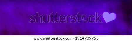 Banner of purple and violet lights makes hear shape bokeh at the right. Romantic, love, Valentines day relationship dark background concept with copy space