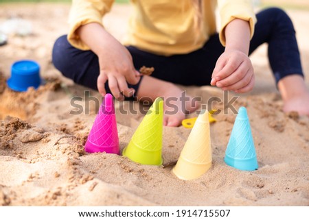 Different colors molds ice cream for sand. On background little cute child play with sand. Joy and play at summer outdoor. Great vacation with children.
