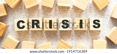 The word CRISIS consists of wooden cubes with letters, top view on a light background. Work space.