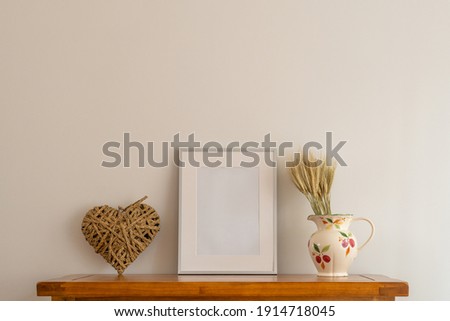 close up of room interior  oak side board with  mock up silver picture frame,rattan heart and china jug  with Wheat Rye  floral arrangement