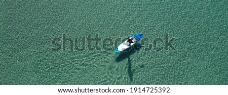 Aerial drone ultra wide photo of fit man on SUP or Stand Up Paddle board in tropical exotic emerald calm sea bay