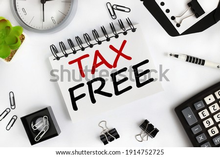 tax free. text on white notepad paper on light background near calculator, plant, table clock.
