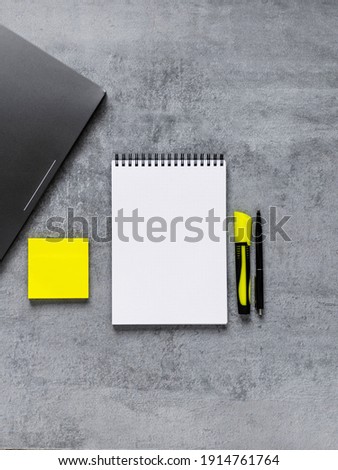 Laptop, phone, and office supplies on a gray concrete table. Workplace. A study table. Remote work. Distance learning. uminous yellow and extremely gray. The color of 2021. Copy space. Vertical