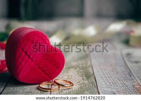 A romantic background for lovers, a box in the form of a heart and two ornate gold rings on a wooden background. Shallow depth of field.
