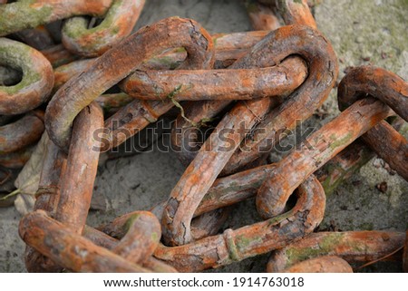 Rustic colourful close up picture of metal chain links connected together and lying on the floor.
