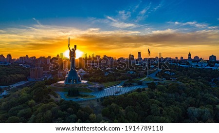Aerial view to the Motherland statue in the Kiev while  summer sunset. The well-known landmarks in Kyiv. Historical monument of Soviet union. Beautiful city Kiev while sunset. Ukraine flag Royalty-Free Stock Photo #1914789118