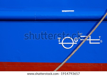 White Plimsoll mark on Blue and red rustproof Metal Hull Side surface of large Boat with mooring Rope
