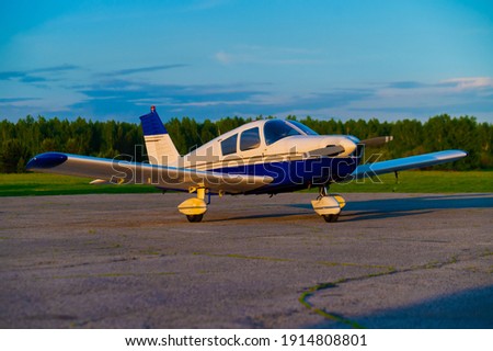 Quadruple aircraft parked at a private airfield. Rear view of a plane with a propeller on a sunset background. Royalty-Free Stock Photo #1914808801