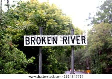 Broken River sign in Eungella National Park, Australia, platypus viewing area. Sign with green trees in the background.