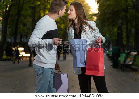 Young couple are arguing about shopping after shopping. Guy and girl share shopping bag.