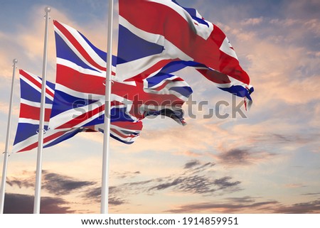 three Flags of Great Britain being waved in the breeze against a sunset sky.