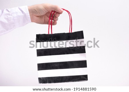 Person shows paper bag, white background, copy space