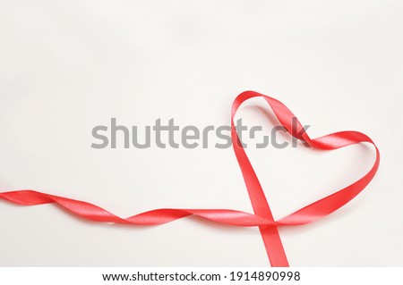 red satin ribbon in the form of a heart on a white background Royalty-Free Stock Photo #1914890998
