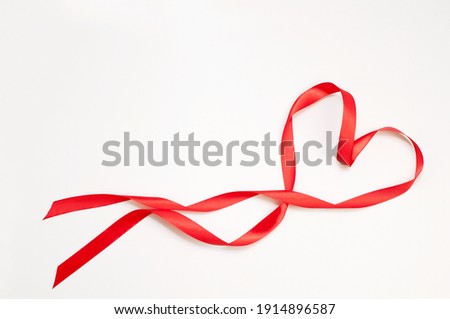 red satin ribbon in the form of a heart on a white background