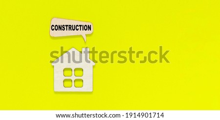 House figurine with pop-up window with text construction on yellow background. Under Construction and Building Concept.