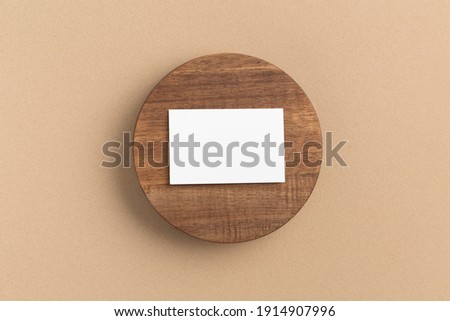 Business card on a wooden round plate on a beige background - top view  flat lay. Minimal mock up

